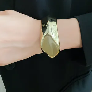Primer plano de un brazalete dorado irregular con una incrustación de resina caqui
