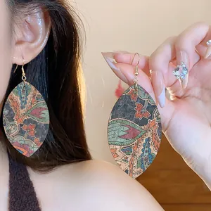 Detailed view of lightweight leaf-shaped dangle earrings with floral print and gold hooks.