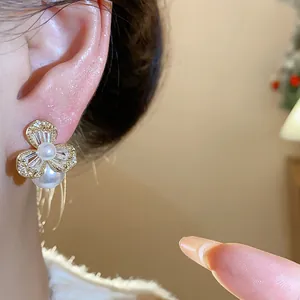 Close-up of elegant French style zircon flower earrings with pearl accents worn on ear