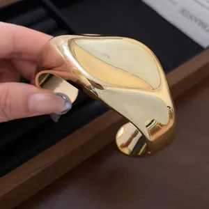 Vista detallada del brazalete de puño dorado brillante irregular con acabado pulido