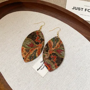 Macro detail view of vintage waterdrop leaf print earrings with intricate bohemian patterns