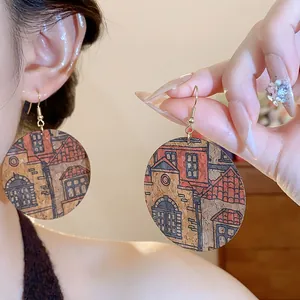 Close-up of round cork earrings with architectural print worn on ear.