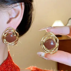 Close-up of elegant gold irregular enamel ear clips with brown diamond center for women