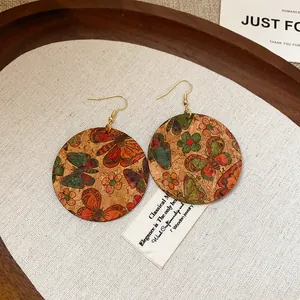 Detail shot of round cork earrings with colorful butterfly and floral printed patterns.