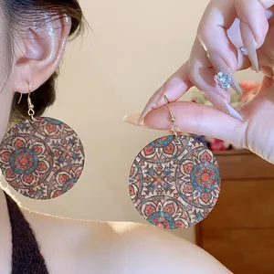 Macro detail of bohemian mandala printed round drop earrings featuring ethnic floral patterns.