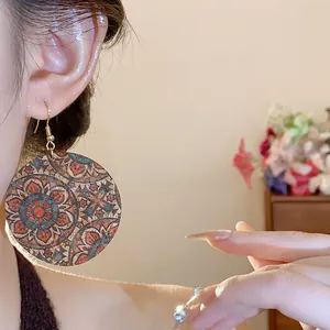 Detailed view of large round drop earrings with vintage mandala print on model's ear