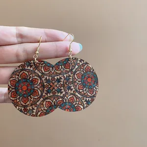 Detail view of large circular cork earrings with colorful mandala floral print pattern