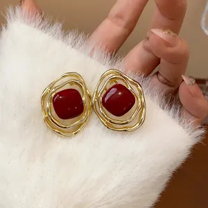 Detail of gold irregular earrings with deep red oil-drop enamel for non-pierced ears.