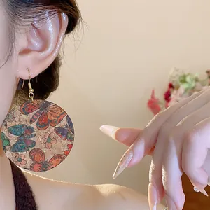 Macro detail of vintage butterfly printed round dangling earrings featuring cork texture