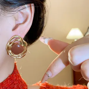 Close-up detail of vintage irregular gold metal ear clips with brown resin center inlay.