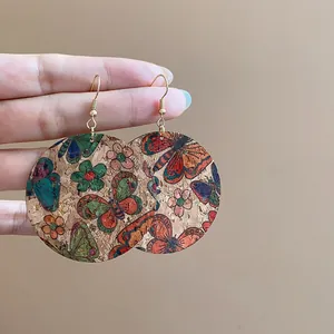 Detailed view of large round cork earrings with colorful butterfly and floral print