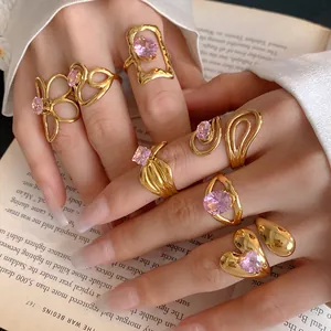 Close-up of golden hollow flower rings with pink zircons on an open book
