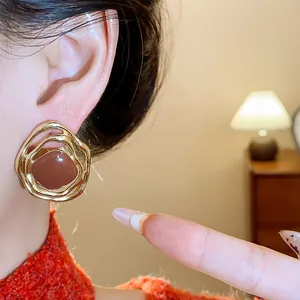 Close-up of irregular golden ear clip with brown oil-drop center worn on a model's ear.