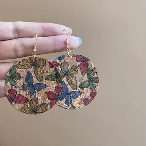 Close-up macro view of bohemian cork drop earrings featuring colorful butterfly print