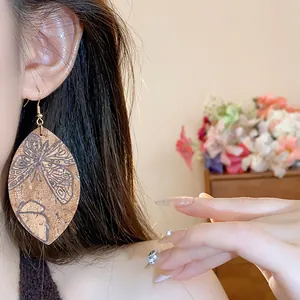Close-up detail of teardrop leaf earrings with vintage butterfly print on model