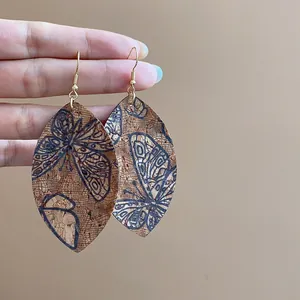 Detailed view of cork textured teardrop earrings with elegant butterfly print patterns