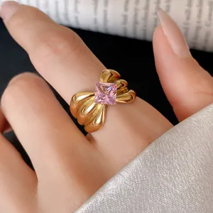 Detailed macro view of a gold-plated stainless steel bow ring with a pink zircon.