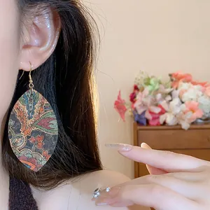 Elegant teardrop leaf pendant earrings with vintage floral print shown on a model