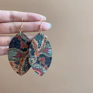 Close-up of bohemian leaf-shaped dangle earrings with vibrant floral pattern prints
