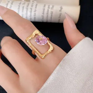 Close-up view of a gold-plated stainless steel ring with a pink zircon in a hollow frame.