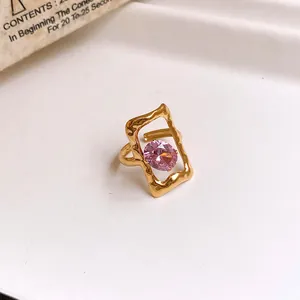 Detail view of a gold stainless steel open ring with hollow frame and pink oval zircon stone