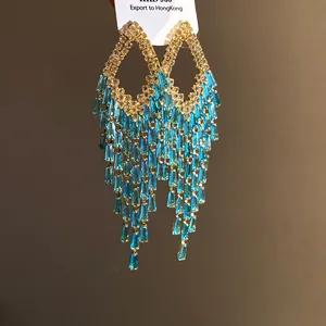 Close-up detail of luxury rhombus tassel earrings featuring blue crystals and silver needle