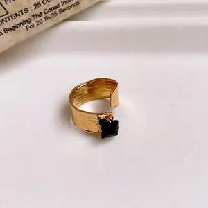 Detail view of hammered gold adjustable open ring featuring a square black gemstone