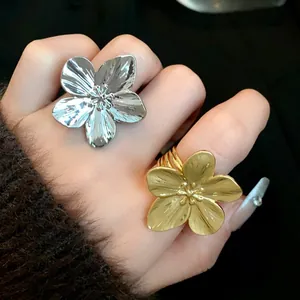 Primer plano detallado de anillos abiertos grandes con forma de flor en oro y plata