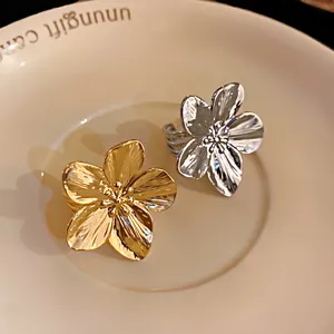 Primer plano de elegantes anillos abiertos con forma de flor chapados en oro y plata en un plato