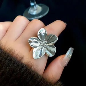 Primer plano de un anillo de flor plateado sobredimensionado llevado en el índice.