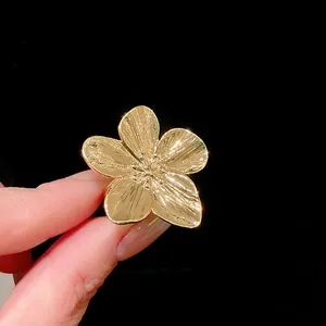 Primer plano de un anillo abierto de flor chapado en oro con pétalos metálicos texturizados