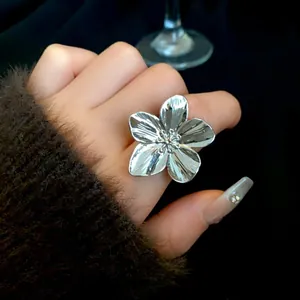 Primer plano de un anillo de flor plateado grande con texturas de pétalos detalladas