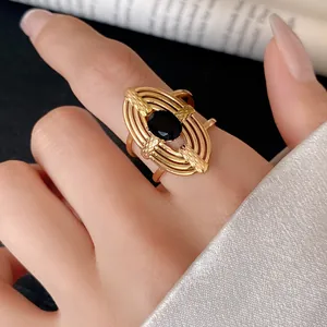 Detail of a gold hollow ring with a black zircon stone on a finger.