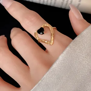 Close-up view of an elegant gold heart-shaped ring featuring a black gemstone detail