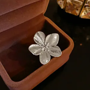 Primer plano de un anillo de flor plateado con pétalos texturizados en estuche.