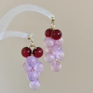 Primer plano de pendientes de racimo de uvas en resina rosa y roja en un expositor