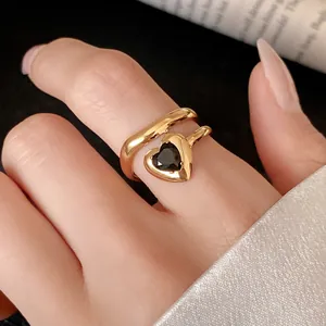 Close-up of a gold heart-shaped zircon ring with a double-layered open design on a finger.