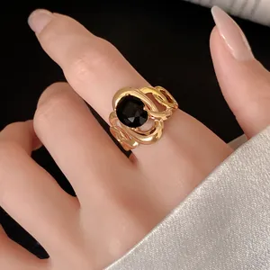 Detailed view of a gold hollow flower ring with a large black zircon on a finger