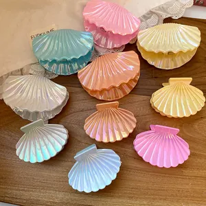 Close-up of colorful iridescent shell-shaped shark hair clips on a wooden surface