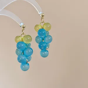 Detalle macro de pendientes de racimo de uva en cuentas de resina azules y verdes de verano