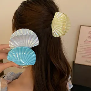 Close-up of iridescent shell-shaped pleated hair clips in blue, white, and yellow