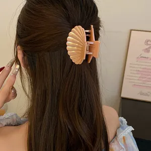 Macro view of pearlescent shell hair claw clip styled in long brown hair