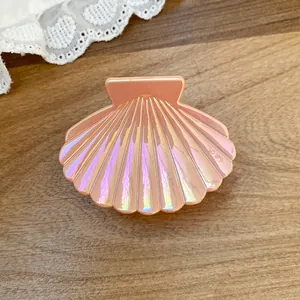 Close-up of a pearlescent shell-shaped hair claw clip with iridescent finish