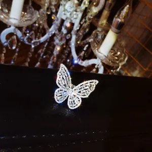 Close-up detail of a luxury sparkling zircon butterfly open ring on black leather surface.