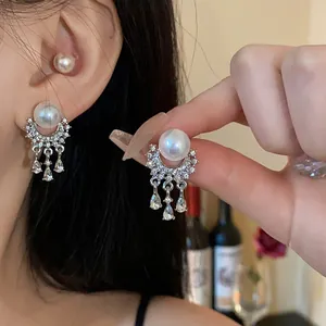 Dettaglio ravvicinato di eleganti orecchini a nappa in argento con perle e strass.