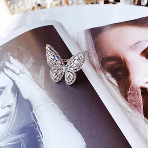 Close-up of elegant silver butterfly ring with shimmering baguette zircons on magazine.