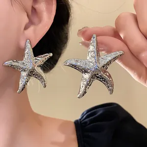Large silver metallic pleated starfish stud earrings shown in a detailed close-up view