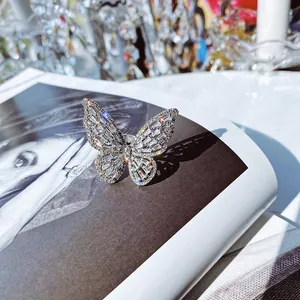 Detailed macro view of a sparkling zircon butterfly open ring placed on a magazine.