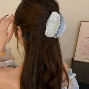 Detailed rear view of shell-shaped hair claw clip with pearlescent finish in brown hair