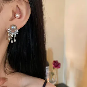 Primo piano di eleganti orecchini a nappa d'argento con perla grigia e gocce di cristallo
